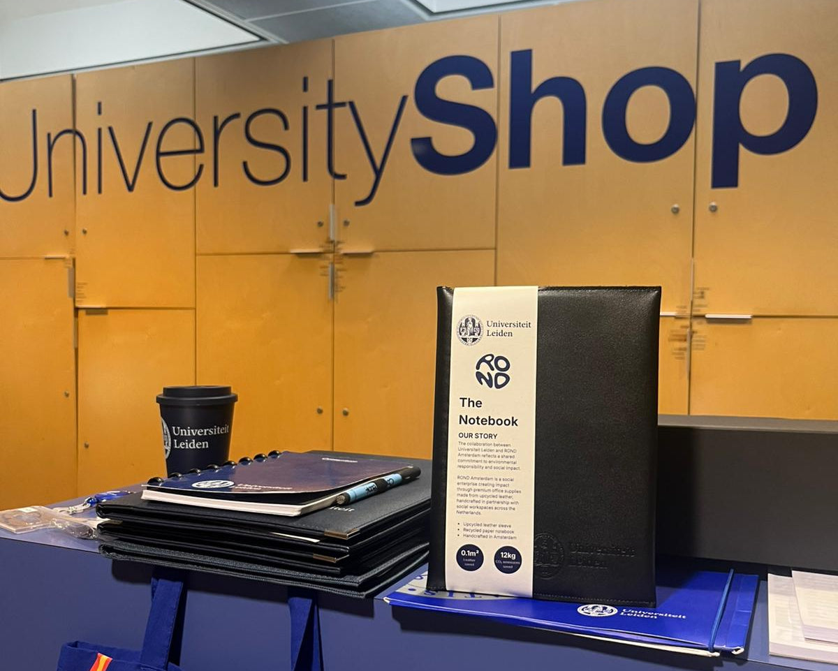 University Shop display with notebooks, a bag, and a coffee cup against a branded wall collaboration ROND Amsterdam