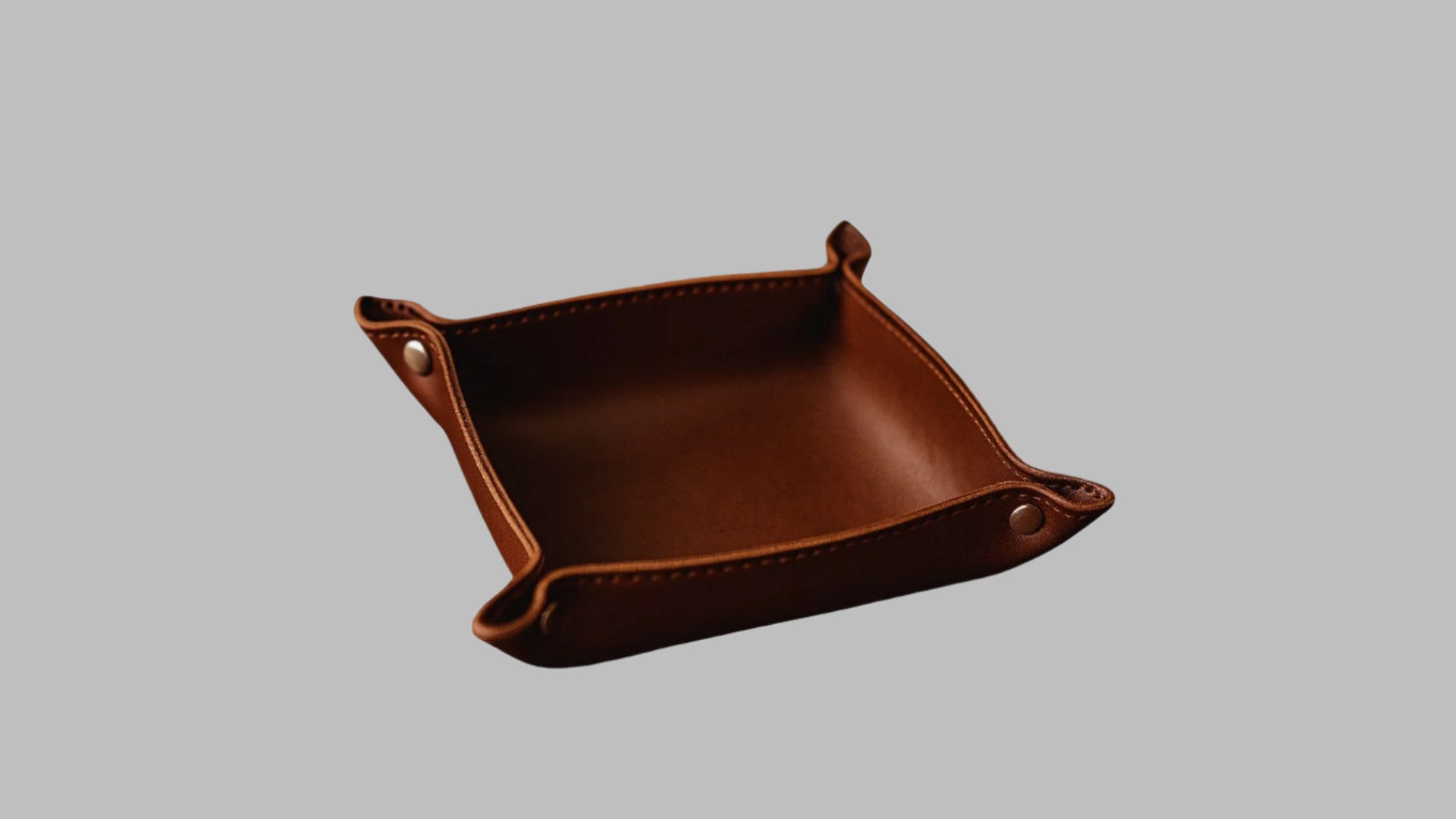 Brown leather tray with rounded corners on a white background